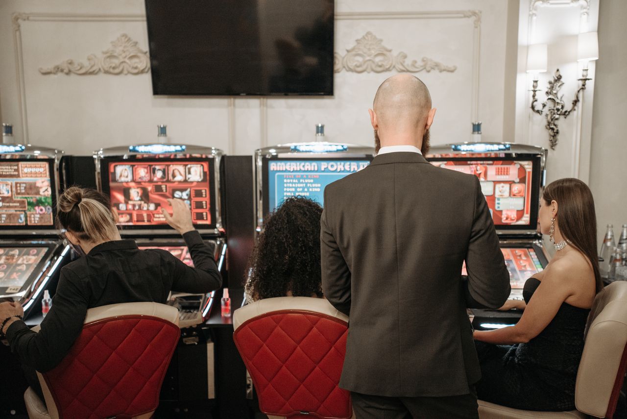 our-services-1 A group of adults engaged in playing slot machines inside a stylish casino setting.