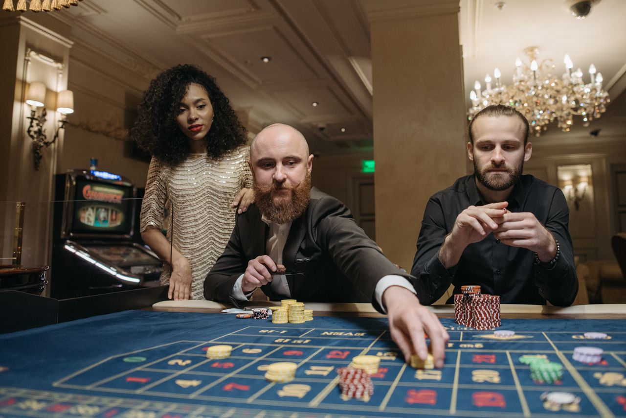 contact-img Group of adults playing roulette in a lavish casino setting, showcasing elegance and thrill.