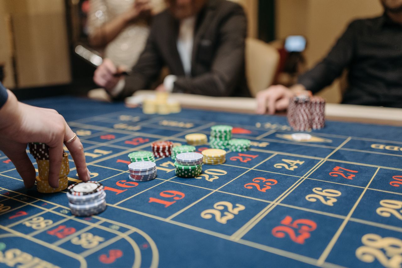 hero-img-01 Hands placing betting chips on a roulette table in an upscale casino setting.