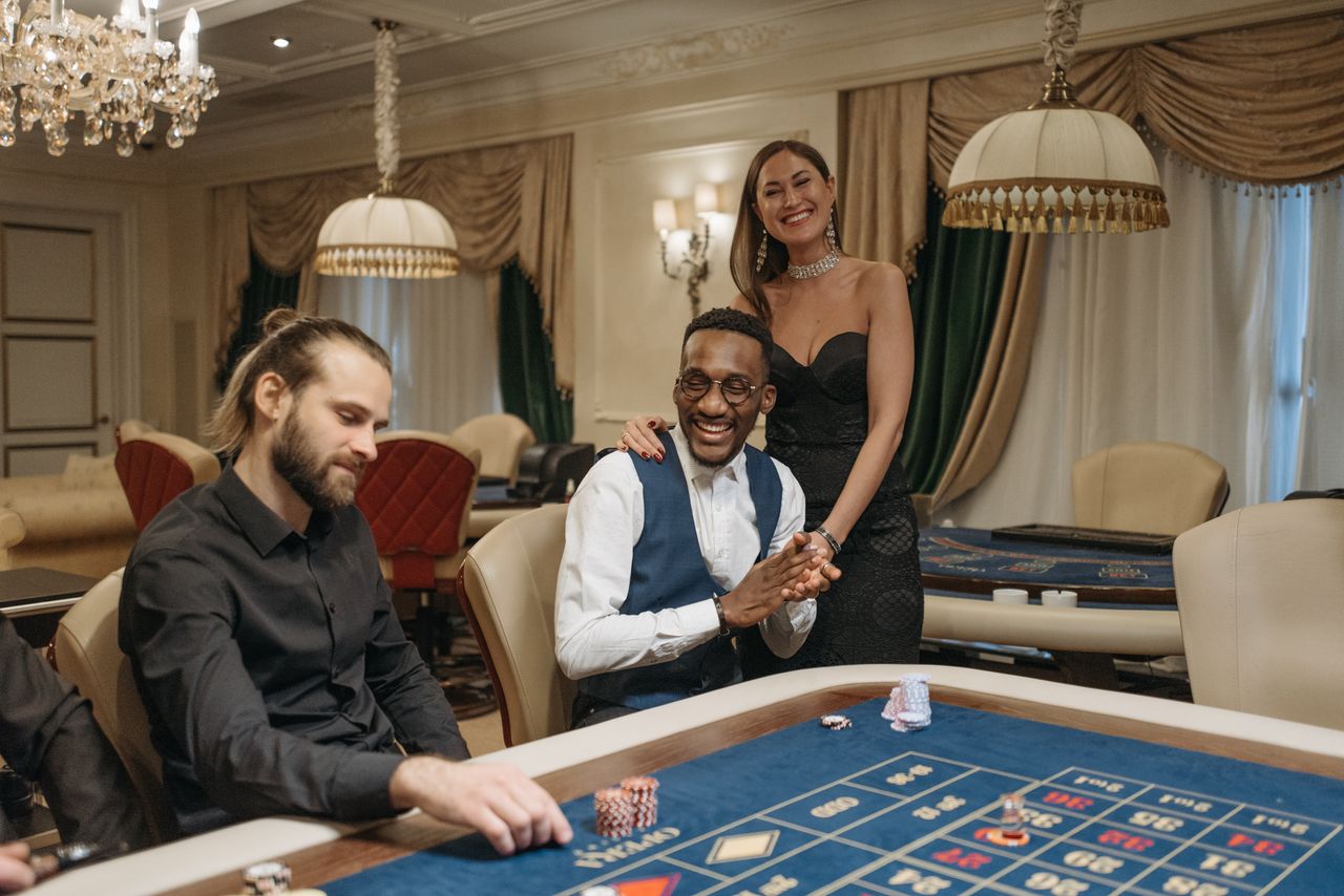 our-services-1 Three people enjoying a night at an elegant casino gambling table.
