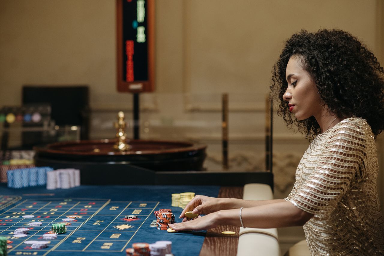gallery-4 Stylish woman in a casino setting, playing roulette with stacks of chips.